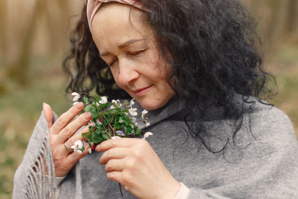 Portrait of a woman enjoying the aroma of spring flowers outdoors.